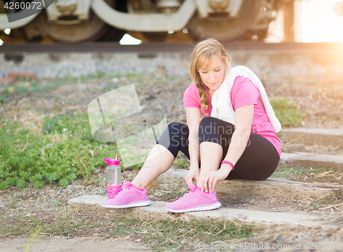 Image of Young Adult Woman Outdoors With Towel and Water Bottle Tying Her