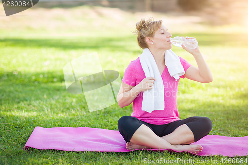 Image of Young Fit Adult Woman Outdoors On Her Yoga Mat with Towel Drinki