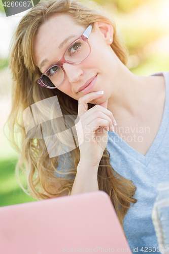 Image of Young Adult Woman Wearing Glasses Outdoors Using Her Laptop.