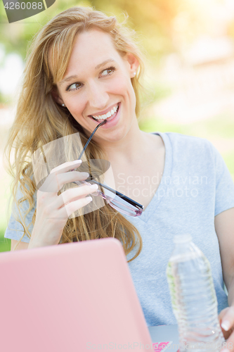Image of Young Adult Woman With Glasses Outdoors Using Her Laptop.