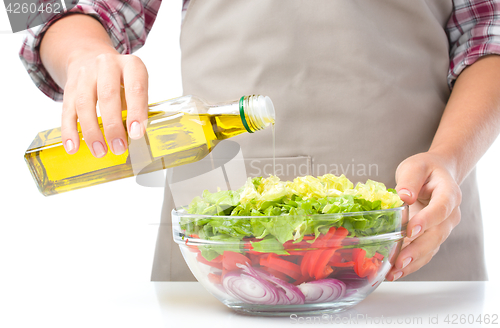 Image of Cook is pouring olive oil into salad