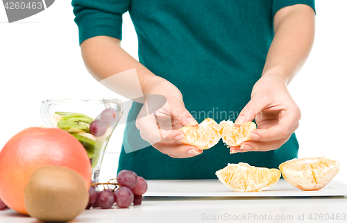 Image of Cook is peeling orange for fruit dessert