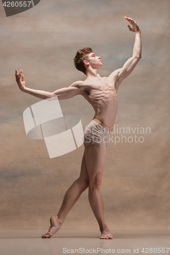 Image of The male ballet dancer posing over gray background