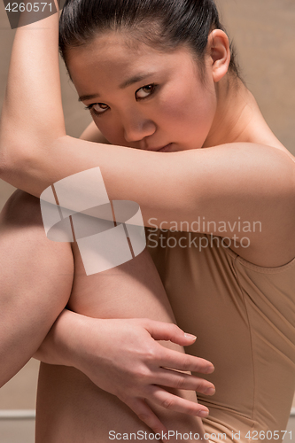 Image of Tired ballet dancer sitting on the wooden chair on a gray background