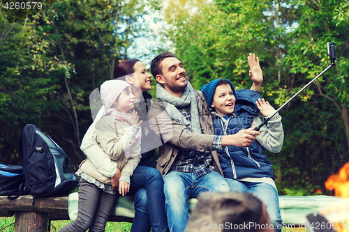 Image of family with smartphone taking selfie near campfire