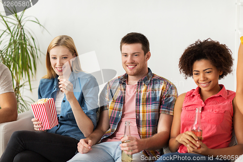 Image of happy friends with popcorn watching tv at home