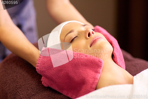 Image of woman having face massage with terry gloves at spa