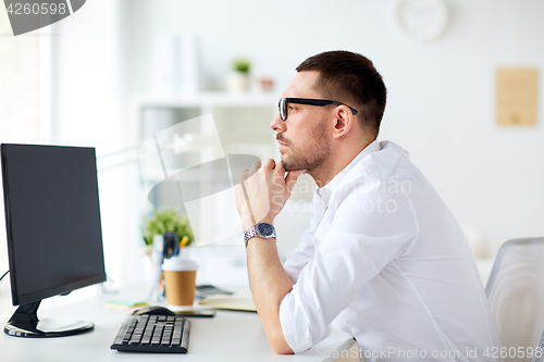 Image of businessman in glasses sitting at office computer