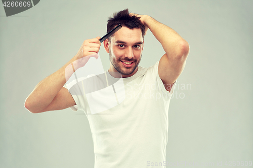 Image of happy man brushing hair with comb over gray