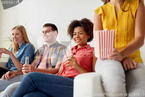 Image of happy friends with popcorn watching tv at home