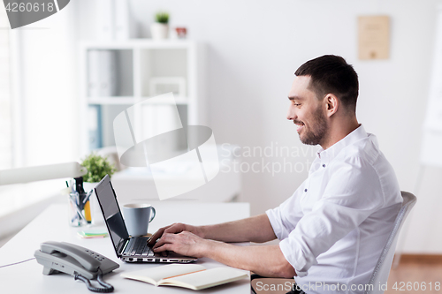 Image of happy businessman with laptop at office