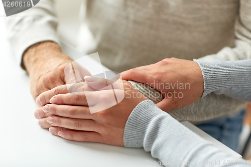 Image of close up of old man and young woman holding hands
