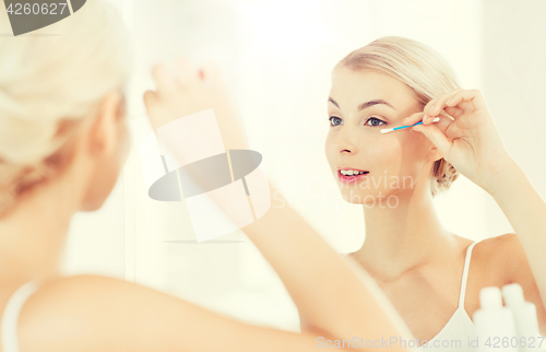 Image of woman fixing makeup with cotton swab at bathroom