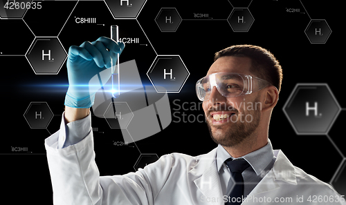 Image of smiling scientist in goggles with test tube