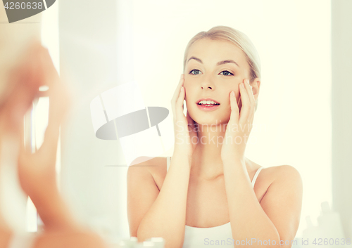 Image of happy young woman looking to mirror at bathroom