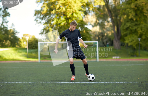 Image of soccer player playing with ball on football field