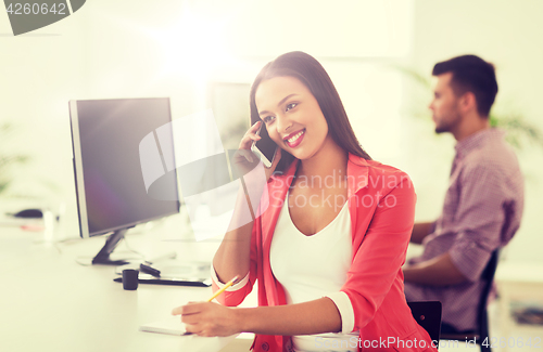 Image of businesswoman calling on smartphone at office