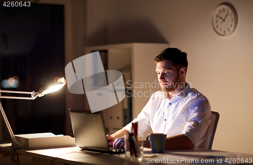 Image of businessman typing on laptop at night office