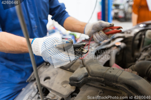 Image of auto mechanic man with cleats charging battery