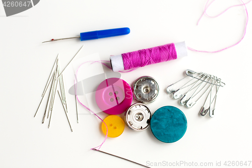 Image of sewing buttons, needles, pins and thread spool