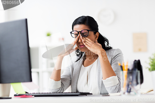 Image of businesswoman rubbing tired eyes at office