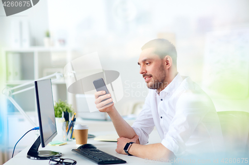 Image of businessman with smartphone and computer at office