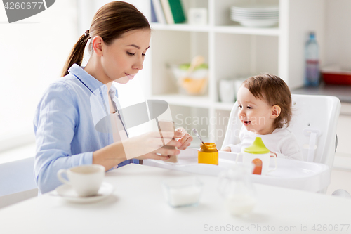 Image of mother with smartphone and baby eating at home 