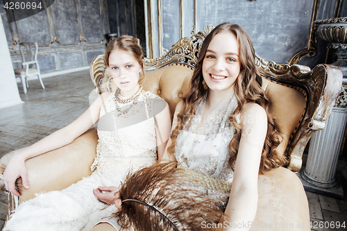 Image of two pretty twin sister blond curly hairstyle girl in luxury house interior together, rich young people concept 