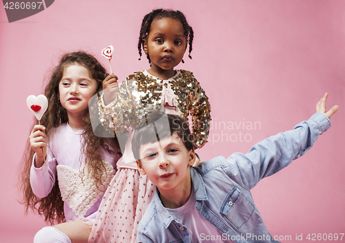 Image of lifestyle people concept: diverse nation children playing together, caucasian boy with african little girl holding candy happy smiling 