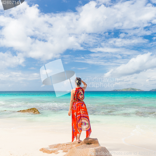 Image of Woman enjoying Anse Patates picture perfect beach on La Digue Island, Seychelles.