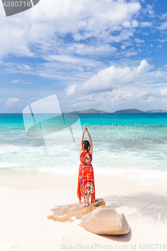 Image of Woman enjoying Anse Patates picture perfect beach on La Digue Island, Seychelles.