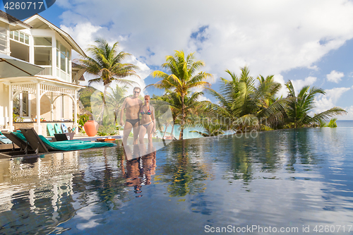 Image of Couple relaxing by luxury hotel swimming pool.