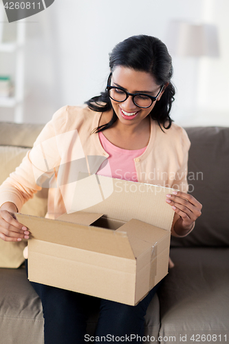 Image of happy young indian woman with parcel box at home