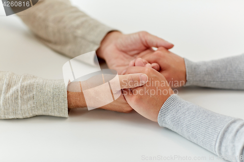 Image of close up of old man and young woman holding hands