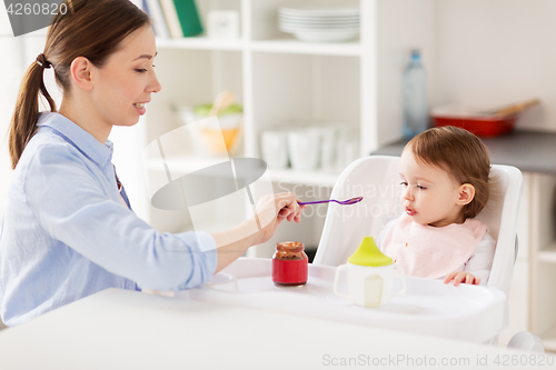 Image of happy mother feeding baby with puree at home
