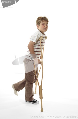 Image of Wincing injured boy using crutches