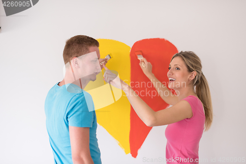 Image of couple are painting a heart on the wall