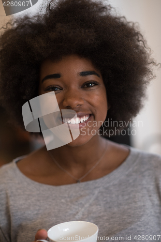 Image of black woman drinking coffee in front of fireplace