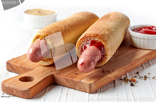 Image of Two hotdogs on wooden cutting board