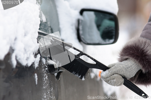 Image of hand cleaning a car from the snow with a brush, closeup