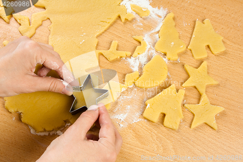 Image of hands making christmas cookies with metal cutter