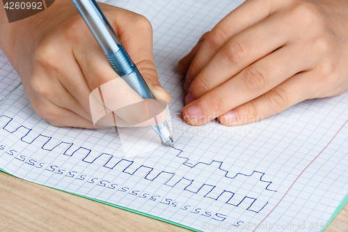Image of hands of child writing in notebook