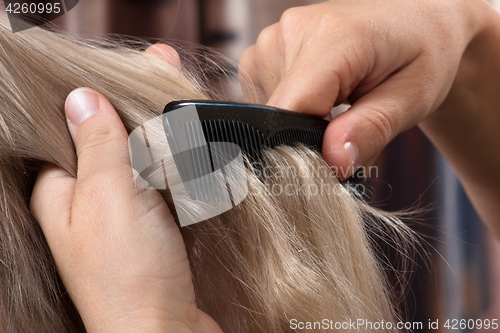 Image of hands of woman combing hair her daughter