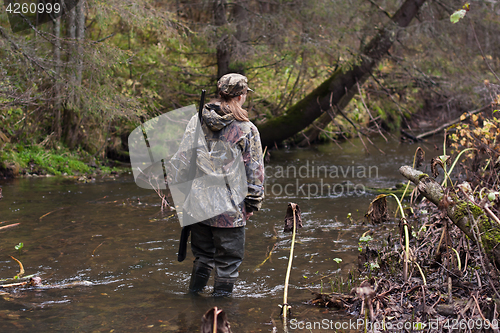 Image of woman hunter crossing the river