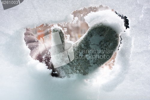 Image of hand in mitten cleaning window of car