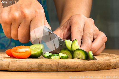 Image of hands chopping cucumber for salad