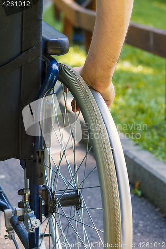 Image of hand of young man on the wheel of wheelchair 