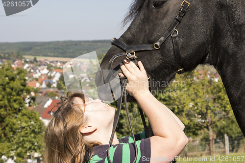 Image of Beautiful young woman with her black horse 