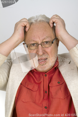 Image of White haired senior with glasses tearing his hair