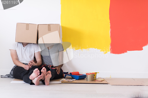 Image of young multiethnic couple playing with cardboard boxes